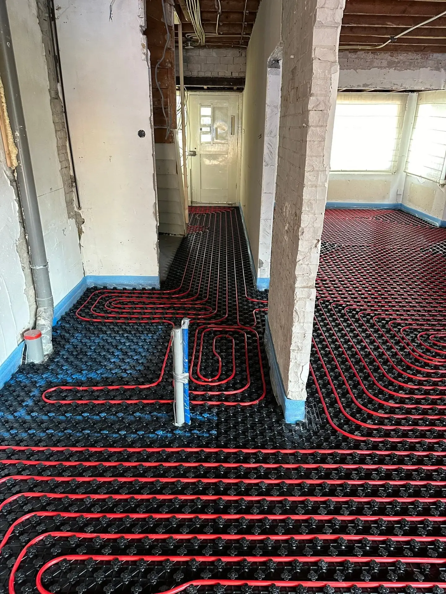 Vloerverwarmingsleidingen in noppenplaten op de begane grond van een woning in verbouwing